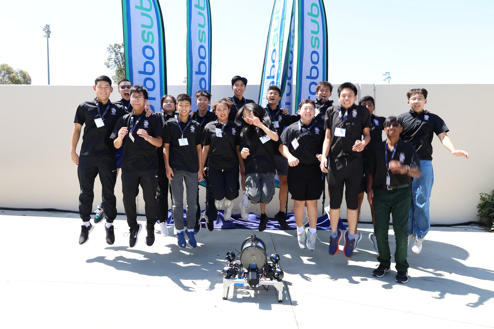 Team jumping for group photo with AUV at RoboSub
